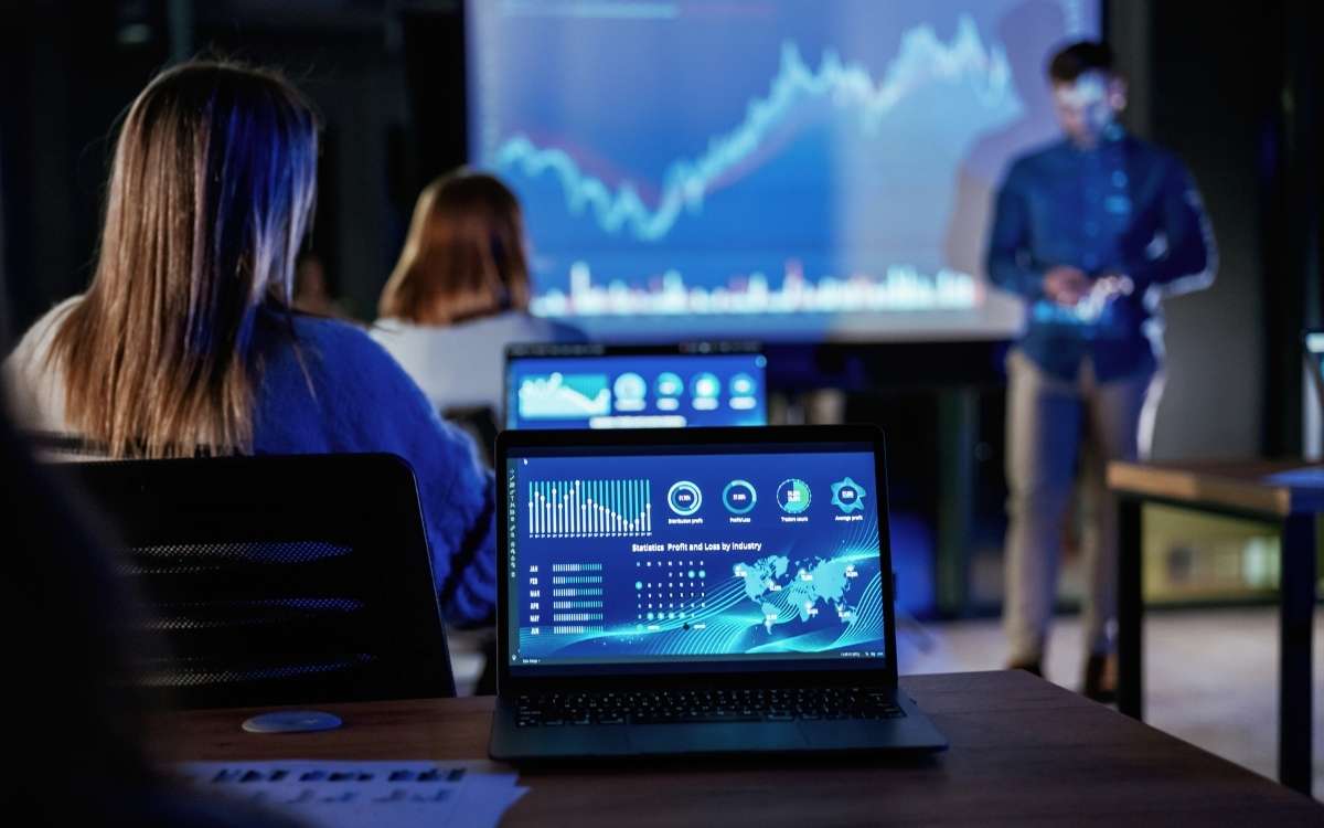 Business presentation on financial data and global payments trends, with laptop dashboards and charts displayed on a screen.